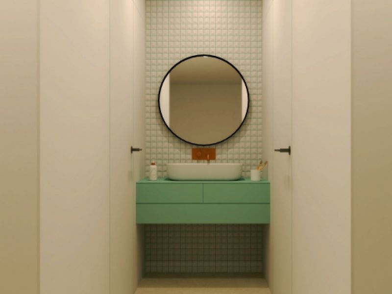 Baño con espejo circular y mueble en color verde agua
