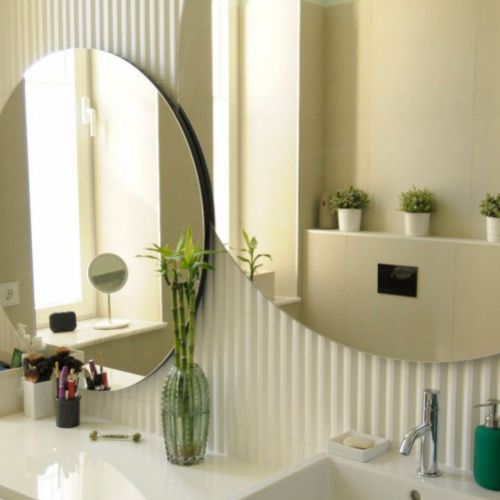 Baño con espejos circulares sobre pared cerámica y elementos decorativos de plantas